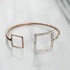 Gold bracelet with two squares encrusted with cubic zirconia on white background