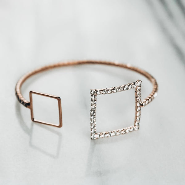 Gold bracelet with two squares encrusted with cubic zirconia on white background